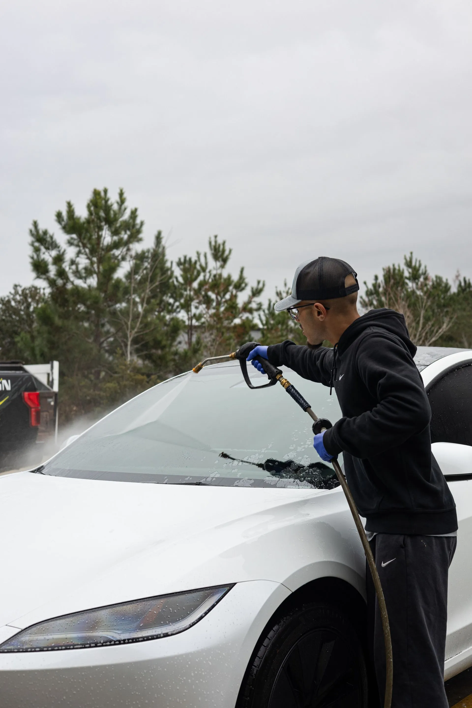 Pressure rinsing a white Tesla before the wash stage
