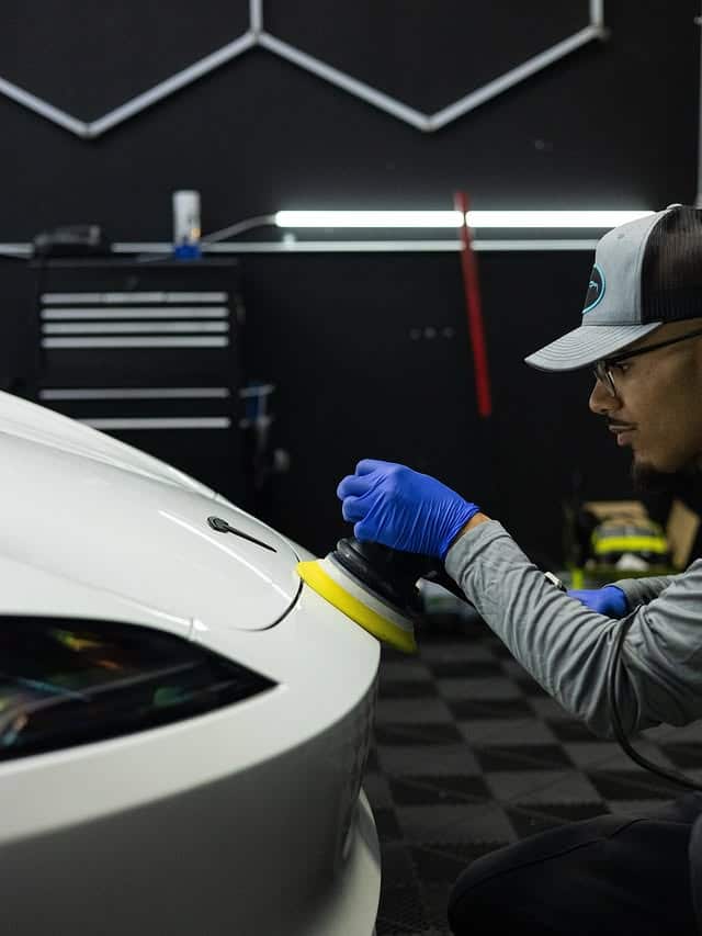 Machine polishing the fender of a white Tesla